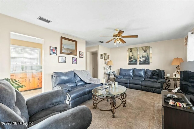 living area featuring carpet flooring, visible vents, and ceiling fan