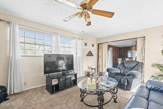 living area featuring baseboards, carpet, a ceiling fan, and a textured ceiling