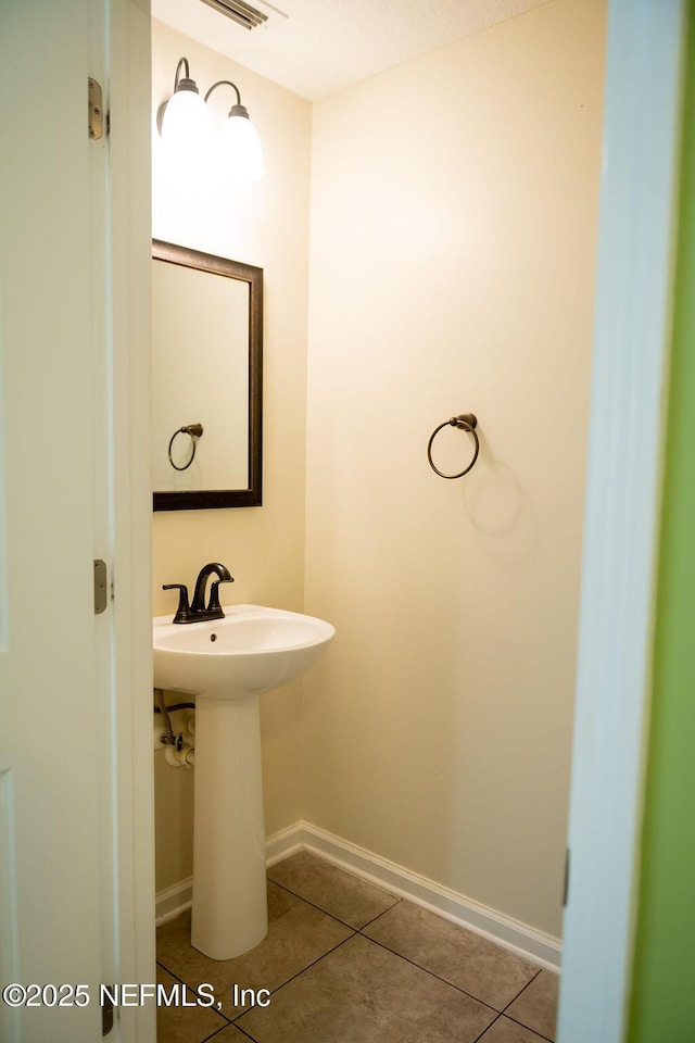 bathroom with tile patterned flooring, baseboards, and a sink