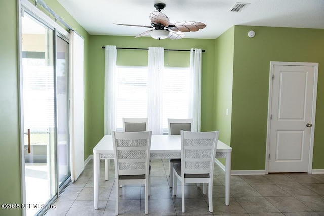 dining space with light tile patterned flooring, a ceiling fan, visible vents, and baseboards