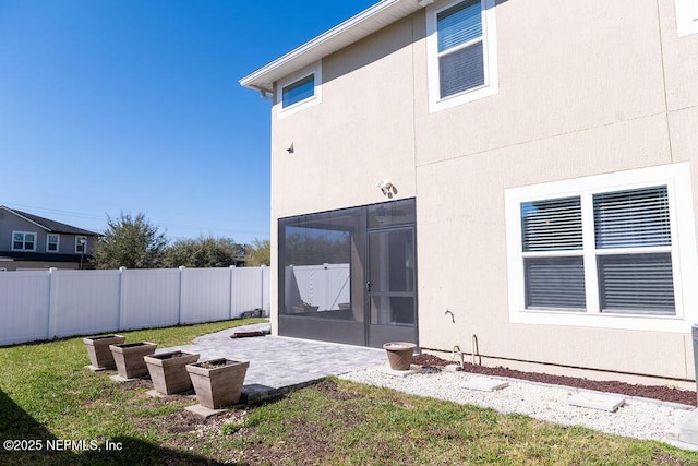 back of property with fence, stucco siding, a yard, a sunroom, and a patio area