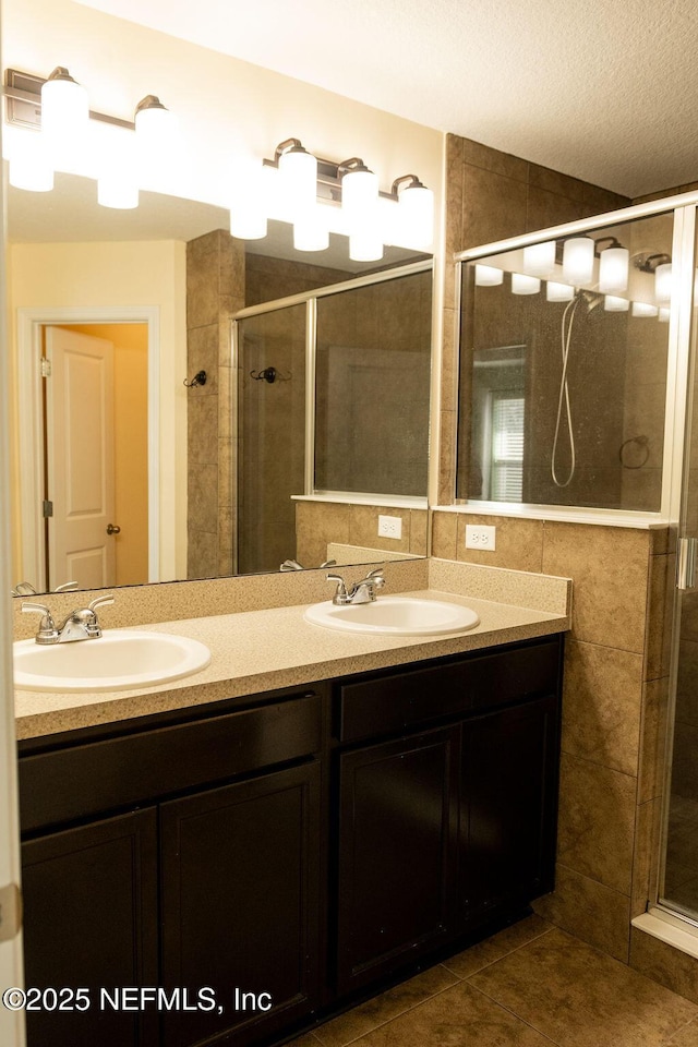 full bathroom featuring a sink, a stall shower, and double vanity