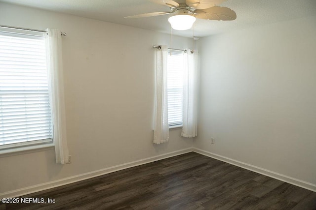 unfurnished room featuring a wealth of natural light, baseboards, dark wood-type flooring, and ceiling fan