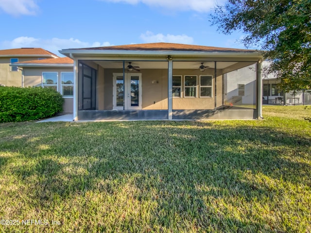back of house with stucco siding, a lawn, a ceiling fan, and a sunroom