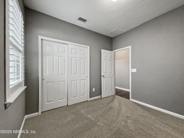 unfurnished bedroom with carpet flooring, baseboards, visible vents, and a closet