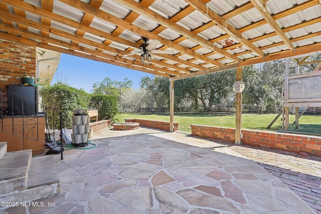 view of patio / terrace with a fire pit, ceiling fan, and fence