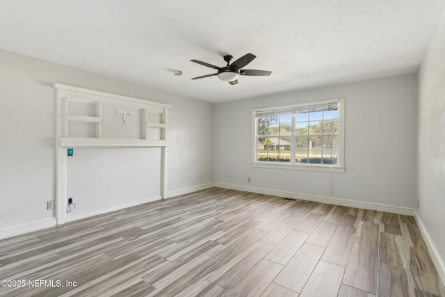 interior space with wood finished floors, a ceiling fan, and baseboards