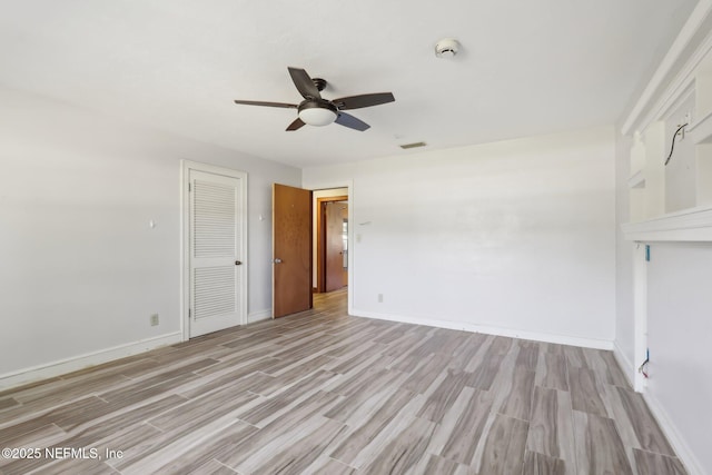 unfurnished room with visible vents, light wood-style flooring, baseboards, and a ceiling fan