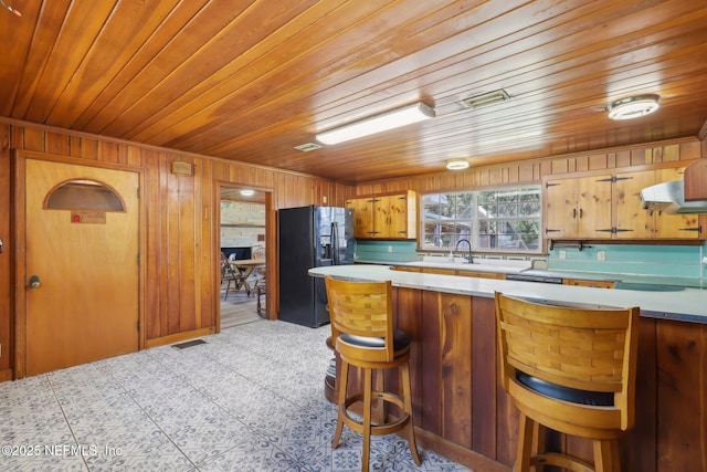 kitchen with visible vents, light countertops, wooden ceiling, a kitchen breakfast bar, and black fridge with ice dispenser