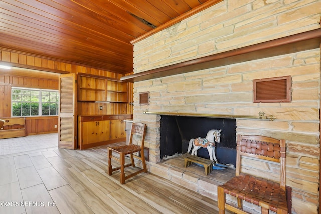 living area featuring wooden walls, wood ceiling, and a fireplace