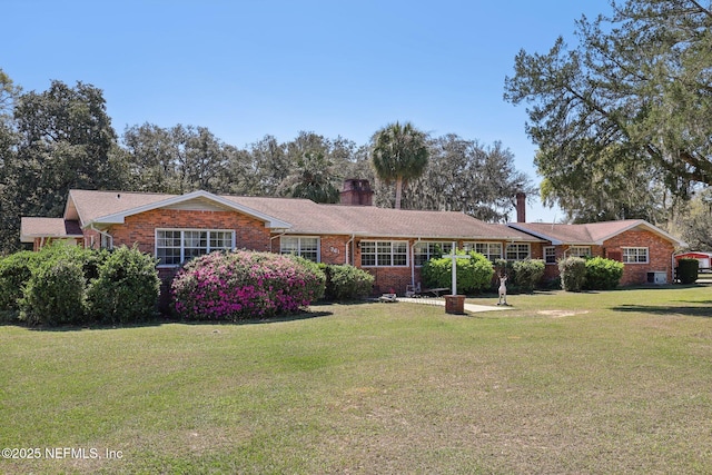 view of front of property featuring a front yard, brick siding, and a chimney