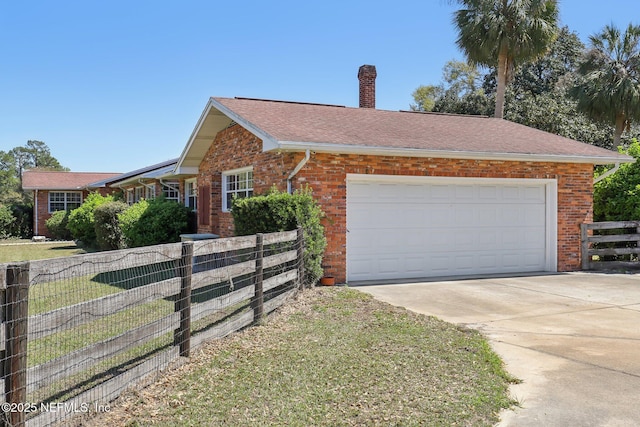 ranch-style house featuring brick siding, concrete driveway, a chimney, and fence