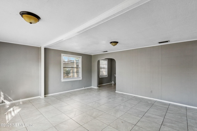 spare room featuring arched walkways, visible vents, baseboards, and light tile patterned floors