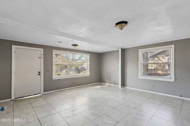 spare room featuring baseboards and a textured ceiling