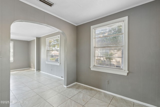 empty room featuring visible vents, arched walkways, light tile patterned flooring, crown molding, and baseboards