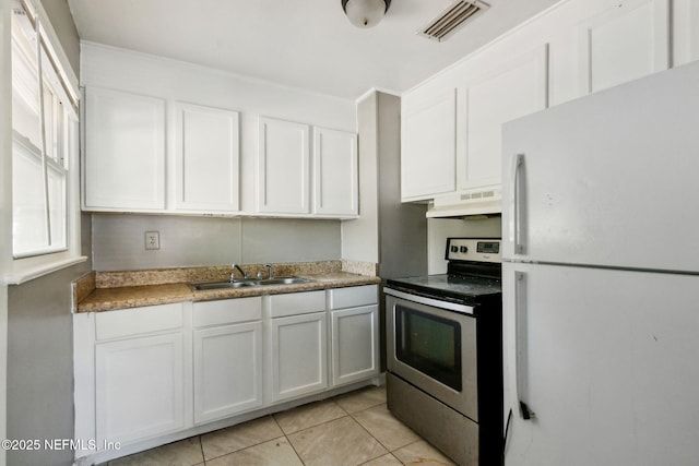 kitchen featuring visible vents, a sink, under cabinet range hood, freestanding refrigerator, and stainless steel electric range oven