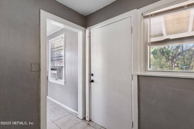 foyer entrance with cooling unit, light tile patterned flooring, and baseboards