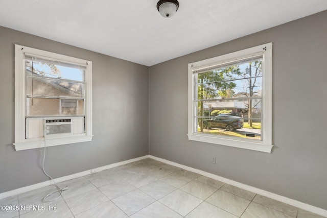 spare room with light tile patterned floors, cooling unit, and baseboards