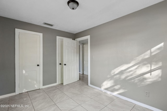 unfurnished bedroom with tile patterned flooring, visible vents, and baseboards