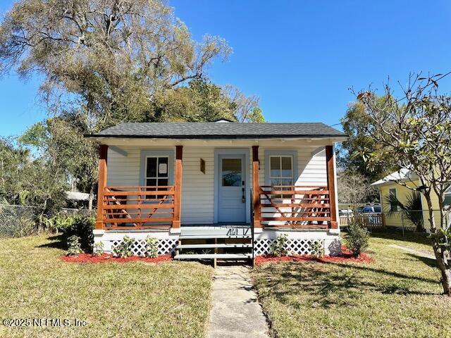 bungalow-style home featuring a porch, a front lawn, and fence