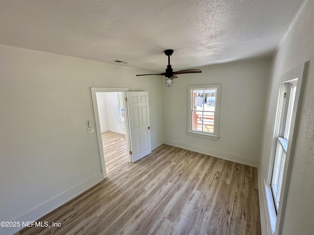 empty room with visible vents, baseboards, wood finished floors, and a ceiling fan