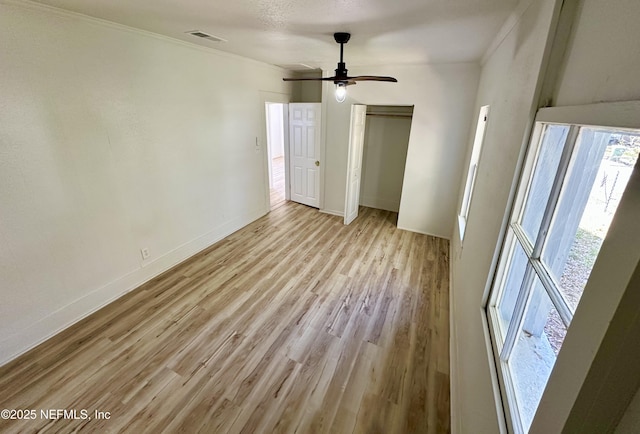 unfurnished bedroom with visible vents, ceiling fan, baseboards, light wood-type flooring, and a closet