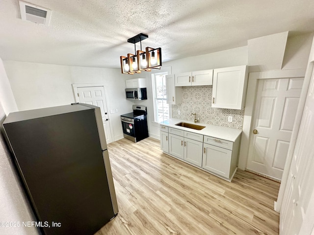 kitchen with a sink, visible vents, light wood-type flooring, and appliances with stainless steel finishes