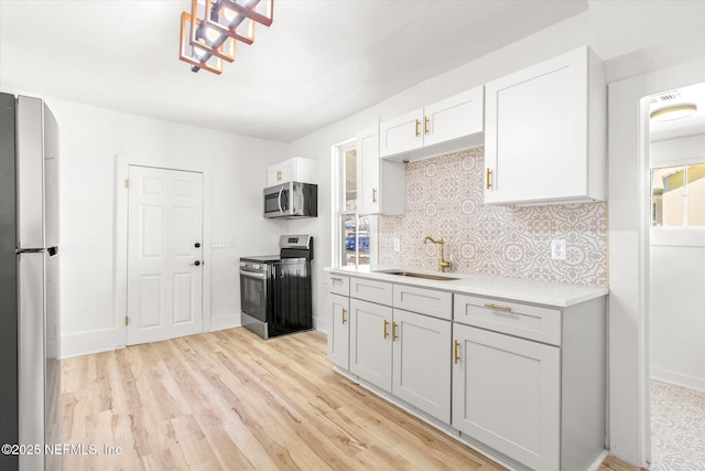 80 Anderson St, Saint Augustine, FL 32084 - kitchen with backsplash, light countertops, appliances with stainless steel finishes, light wood-style floors, and a sink
