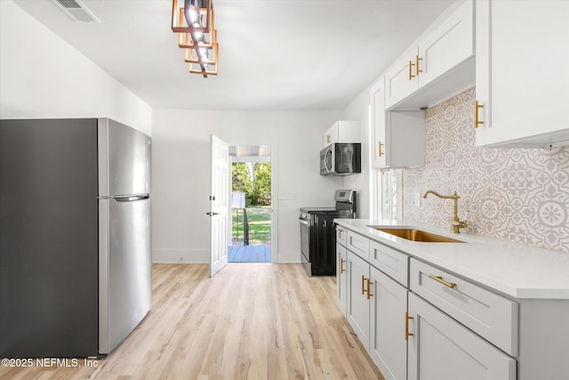 80 Anderson St, Saint Augustine, FL 32084 - kitchen with backsplash, light countertops, light wood-style floors, stainless steel appliances, and a sink