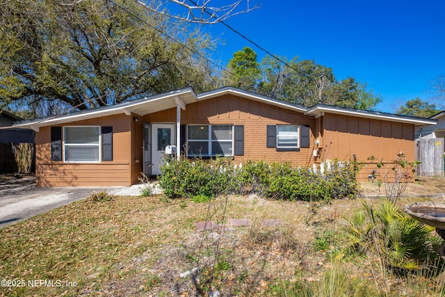 ranch-style house with brick siding, board and batten siding, and fence