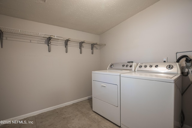 clothes washing area featuring baseboards, light tile patterned floors, laundry area, independent washer and dryer, and a textured ceiling