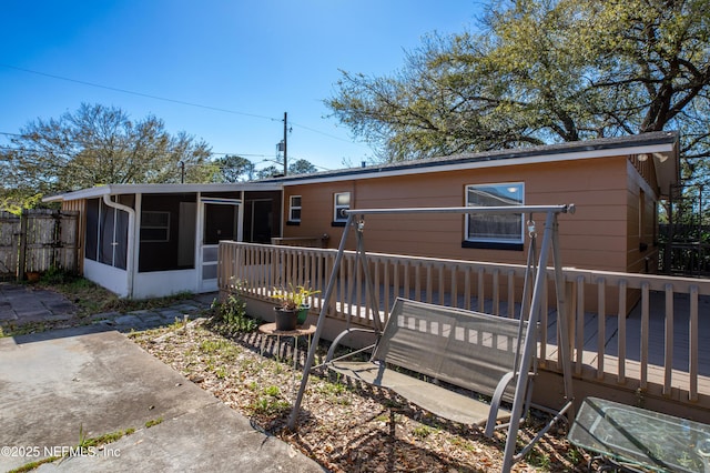 view of front of home with fence, a sunroom, and a wooden deck