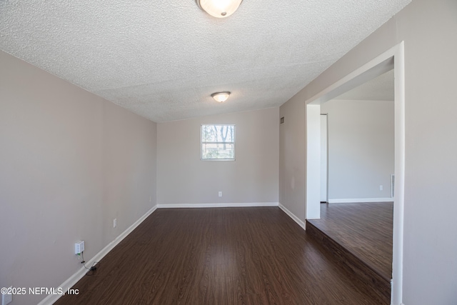 empty room featuring dark wood finished floors, lofted ceiling, baseboards, and a textured ceiling