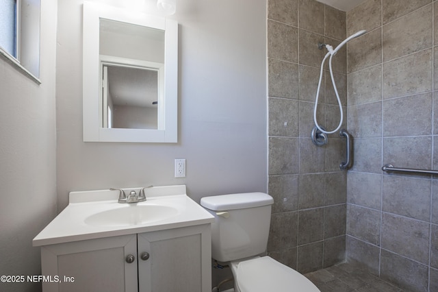 full bathroom featuring tiled shower, toilet, and vanity