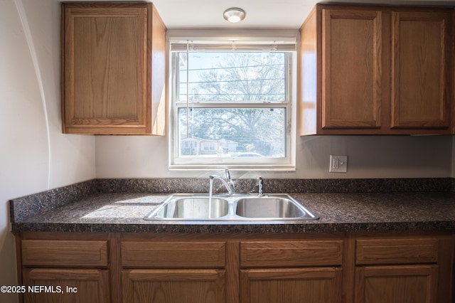 kitchen featuring a sink, dark countertops, and brown cabinetry