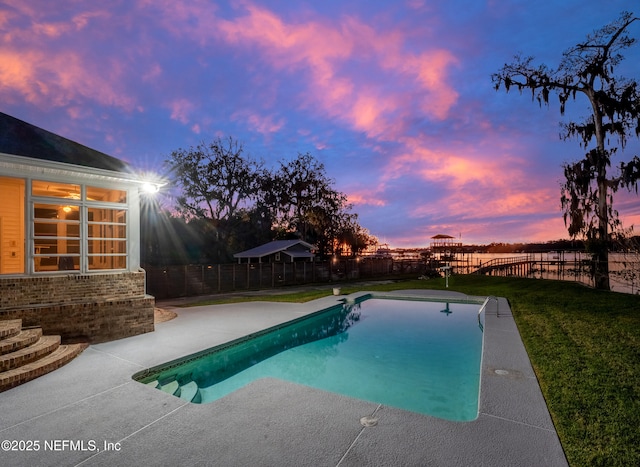 pool at dusk featuring a fenced in pool, a lawn, a fenced backyard, and a patio area