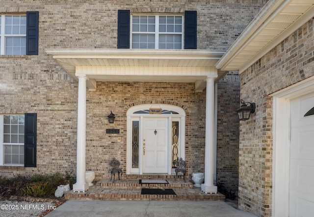 entrance to property featuring a porch and brick siding