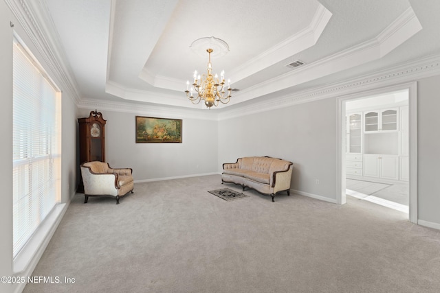 sitting room with a tray ceiling, carpet flooring, visible vents, and a chandelier