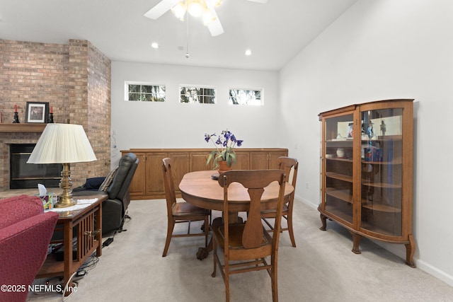 dining space featuring a brick fireplace, baseboards, ceiling fan, light carpet, and recessed lighting