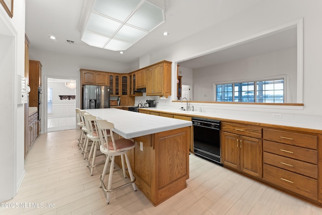 kitchen with a sink, a kitchen island, stainless steel fridge, brown cabinetry, and dishwasher