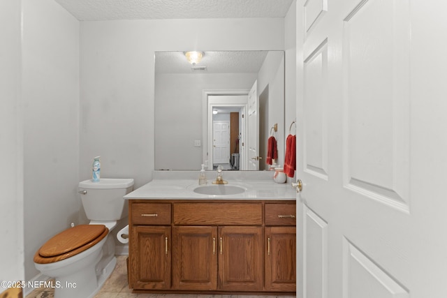 half bath featuring vanity, visible vents, tile patterned flooring, a textured ceiling, and toilet