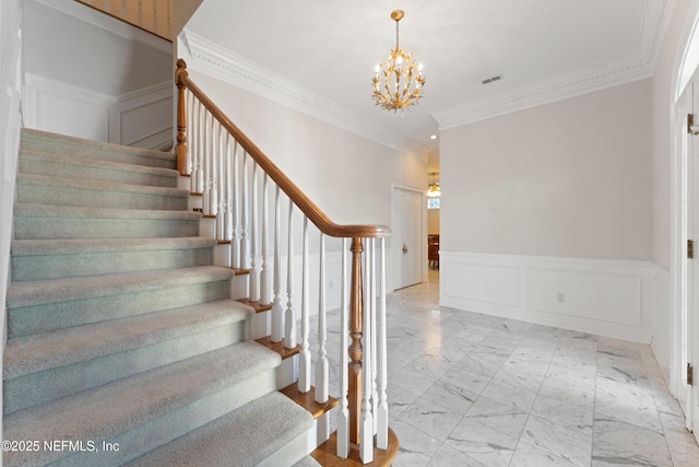 stairs featuring a wainscoted wall, visible vents, an inviting chandelier, a decorative wall, and marble finish floor