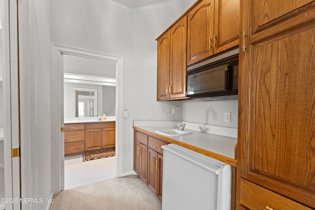 kitchen featuring black microwave, light countertops, white dishwasher, brown cabinetry, and a sink