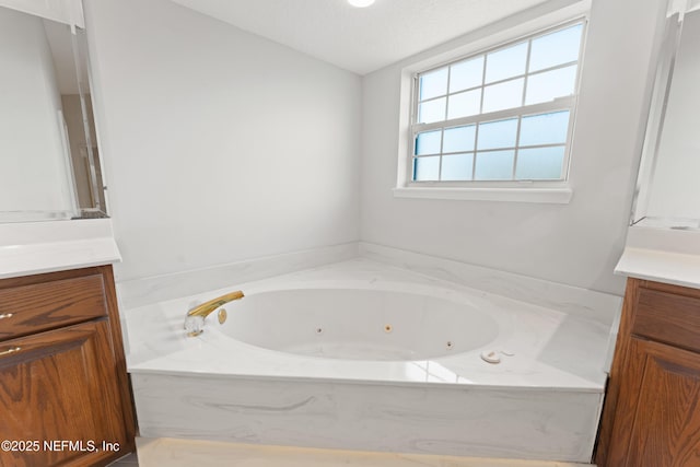 bathroom featuring a whirlpool tub, vanity, and a textured ceiling