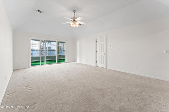 spare room featuring visible vents, baseboards, carpet floors, vaulted ceiling, and a ceiling fan