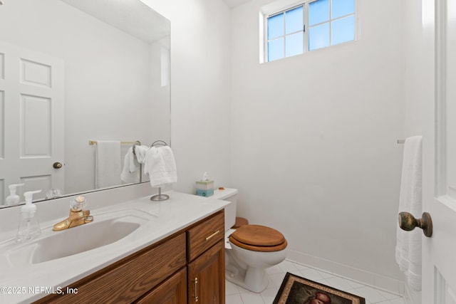 half bathroom featuring tile patterned floors, baseboards, toilet, and vanity