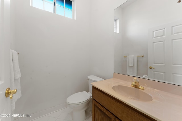 half bath with tile patterned flooring, toilet, vanity, and baseboards