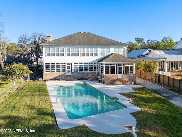 rear view of house with a yard, a fenced backyard, a fenced in pool, and a chimney