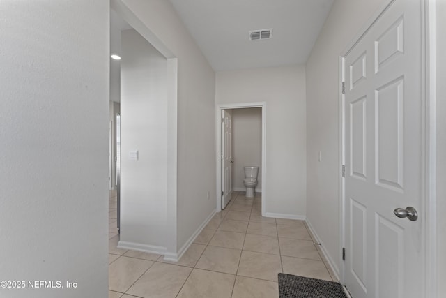 hall with light tile patterned floors, baseboards, and visible vents