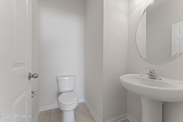 bathroom with tile patterned floors, baseboards, and toilet